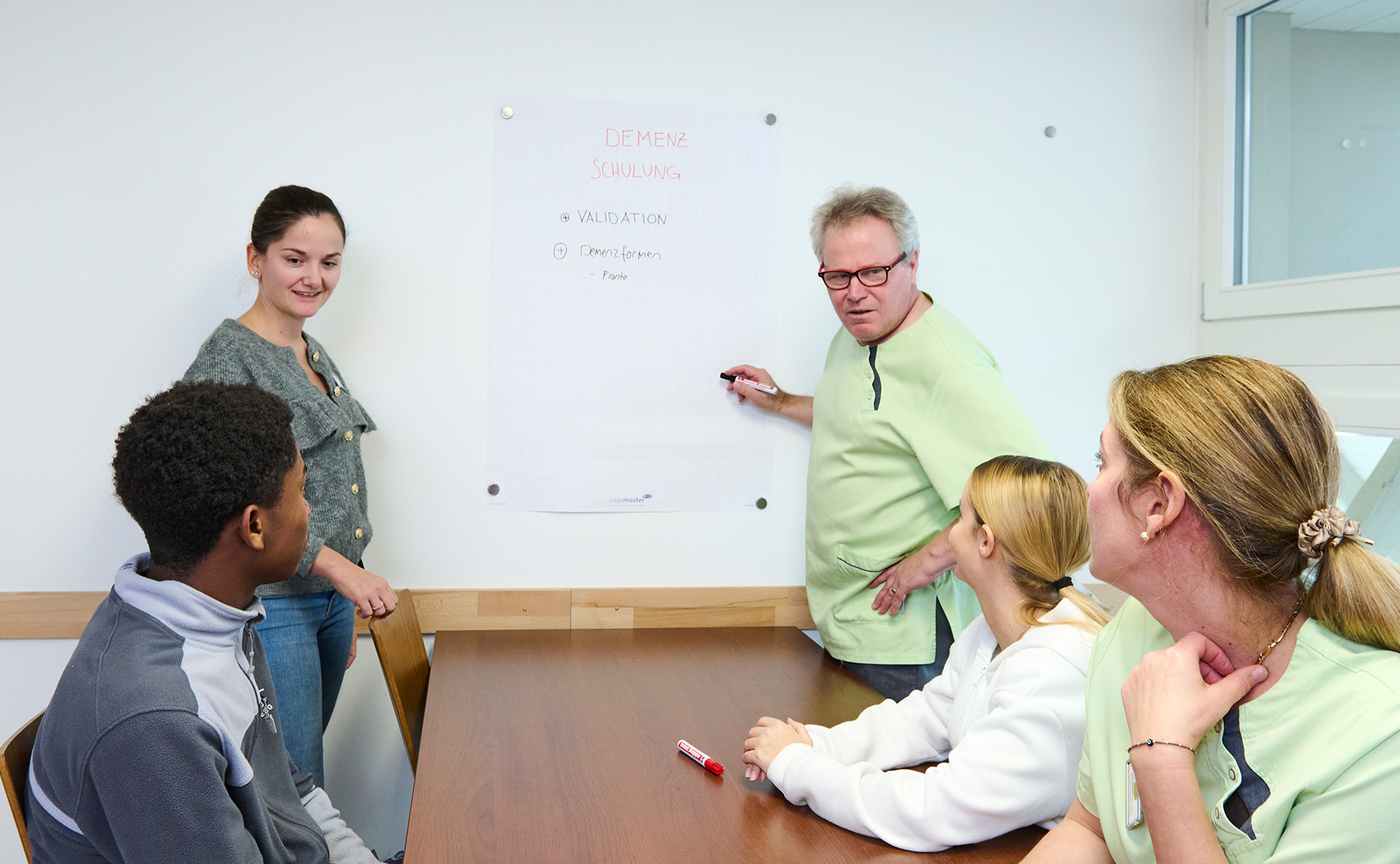 Mitarbeiter bei einer Schulung, sitzen an einem Tisch, schauen auf ein Flipchart