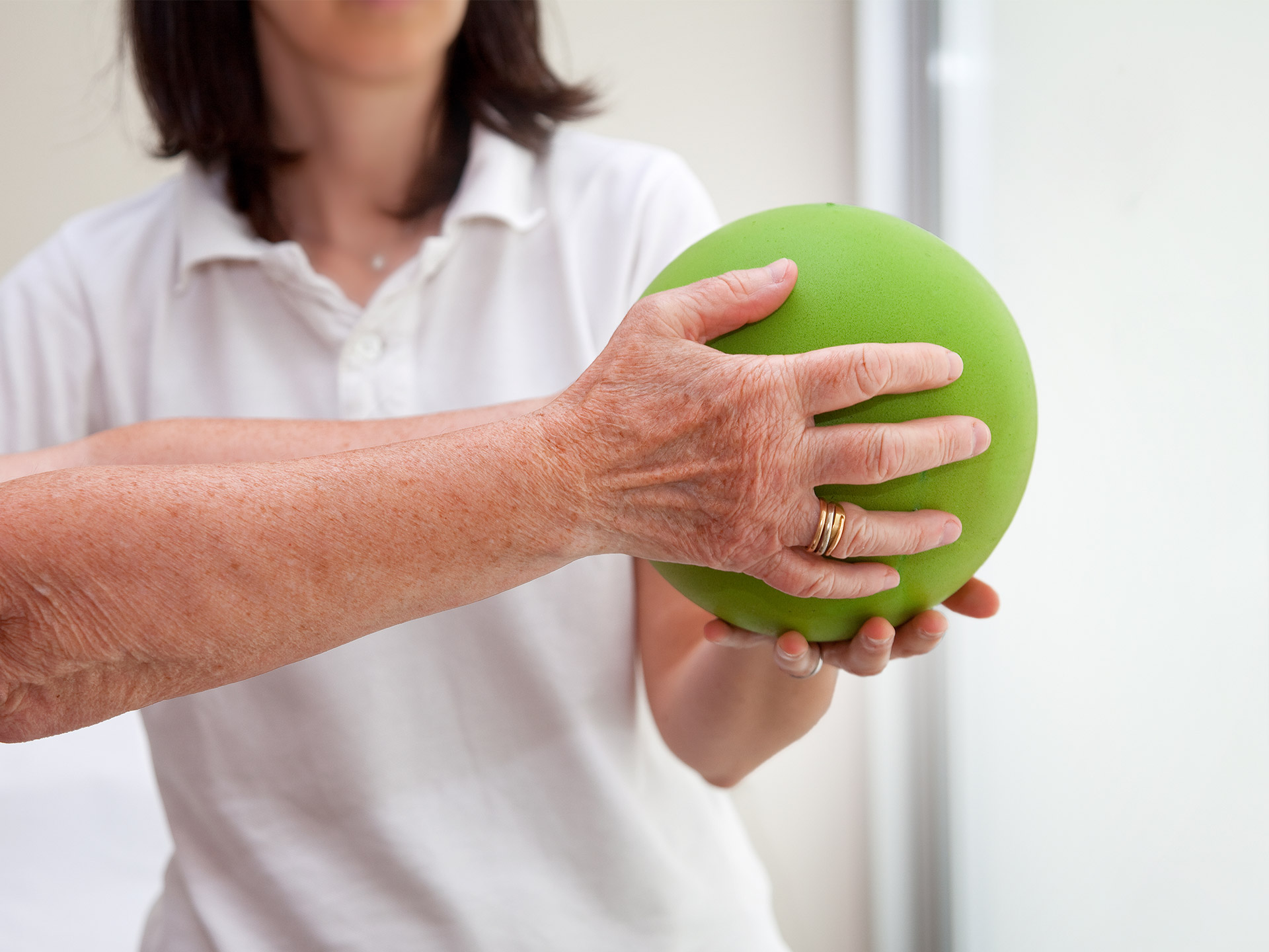 Eine Physiotherapeutin macht eine Übung mit einem Ball mit einem Bewohner
