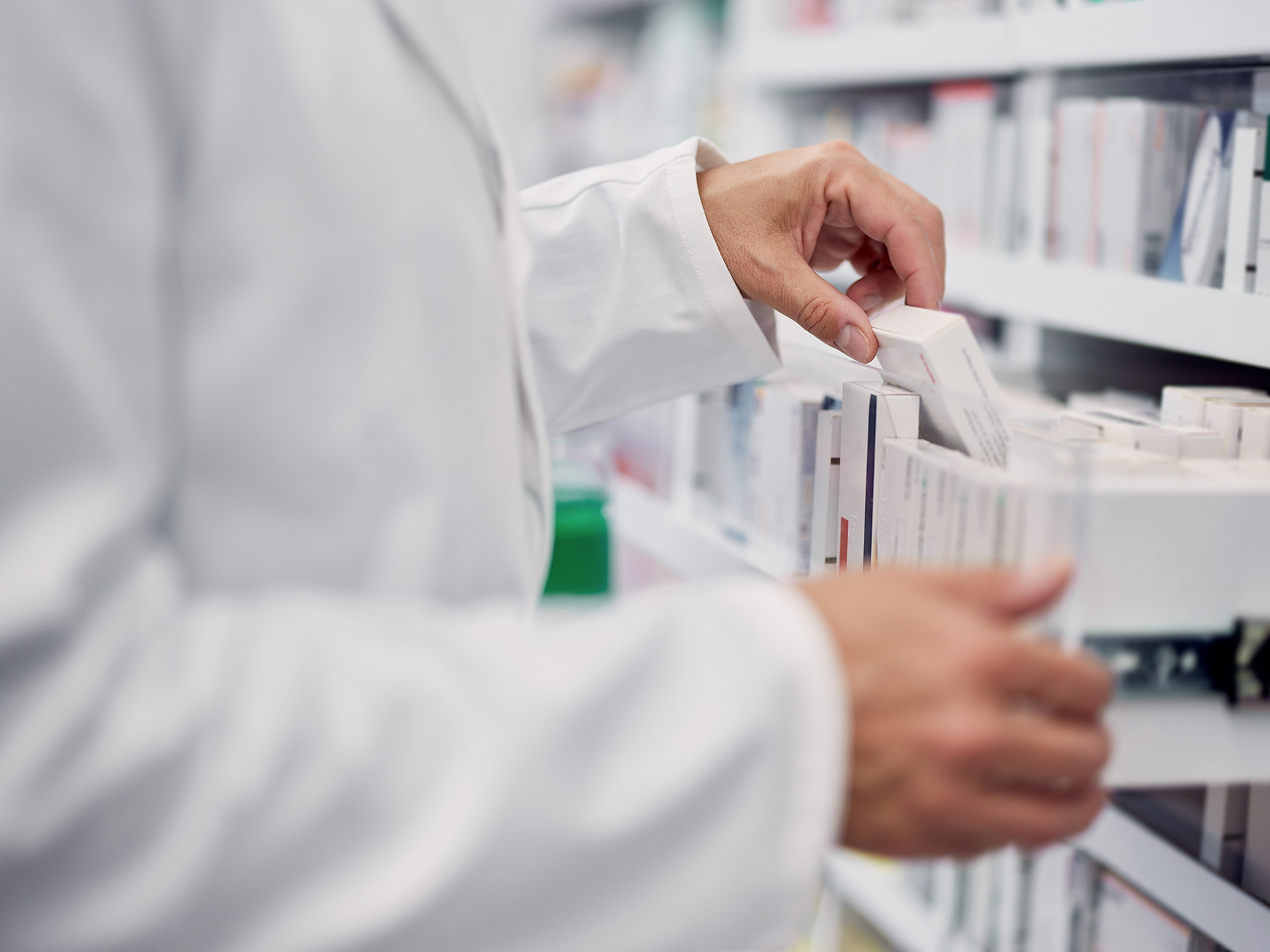 Ein Apotheker steht an einem Regal mit Medikamenten
